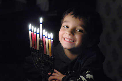 a kid lighting a chanukiyah