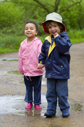 two smiling kids standing in a puddle